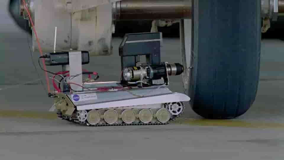Tire Assault Vehicle (basé sur le modèle réduit de Tigre II) en train de percer un pneu de navette spatiale prêt à éclater sous l'avion d'essai CV-990 LSRA (27 juillet 1995).