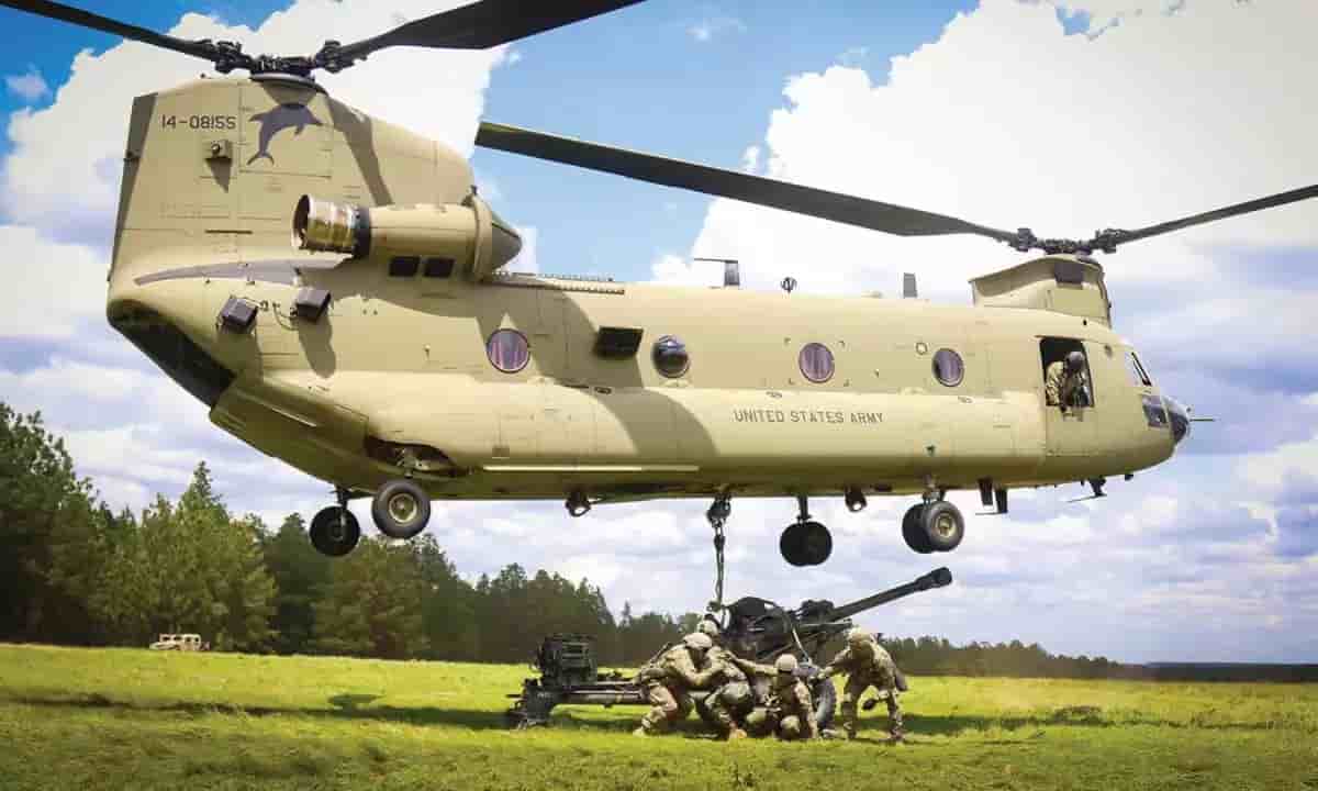 CH-47F Chinook américain en train de transporter une pièce d'artillerie.