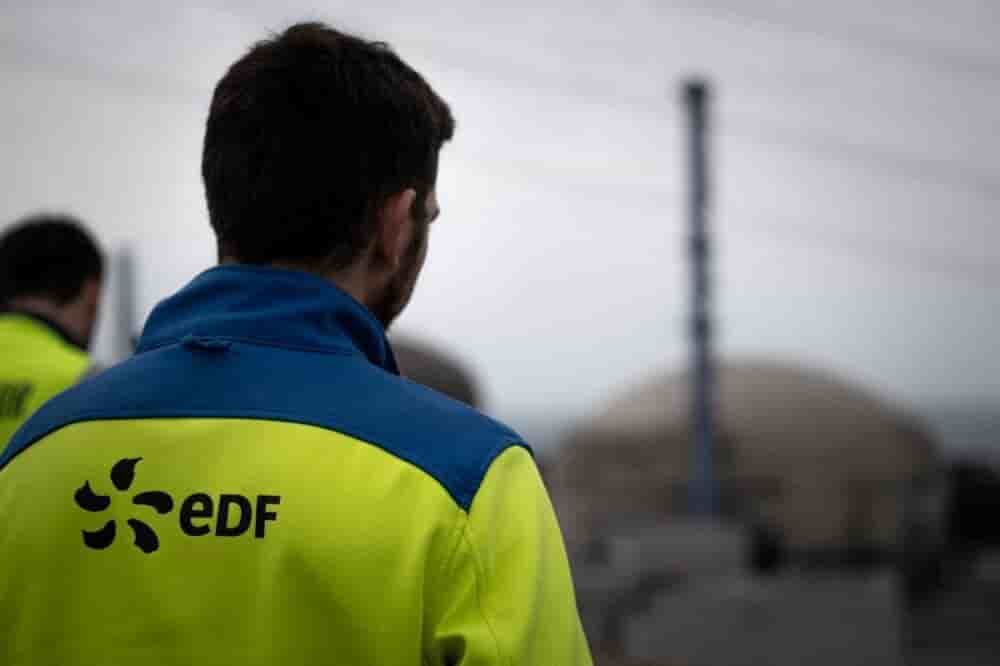 Un agent EDF devant une centrale nucléaire.