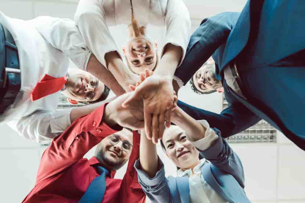 Team of diverse business people stacking their hands together, seen from below - Team of diverse business people stacking their hands together - Team von diversity Geschättsleuten beim Team-building