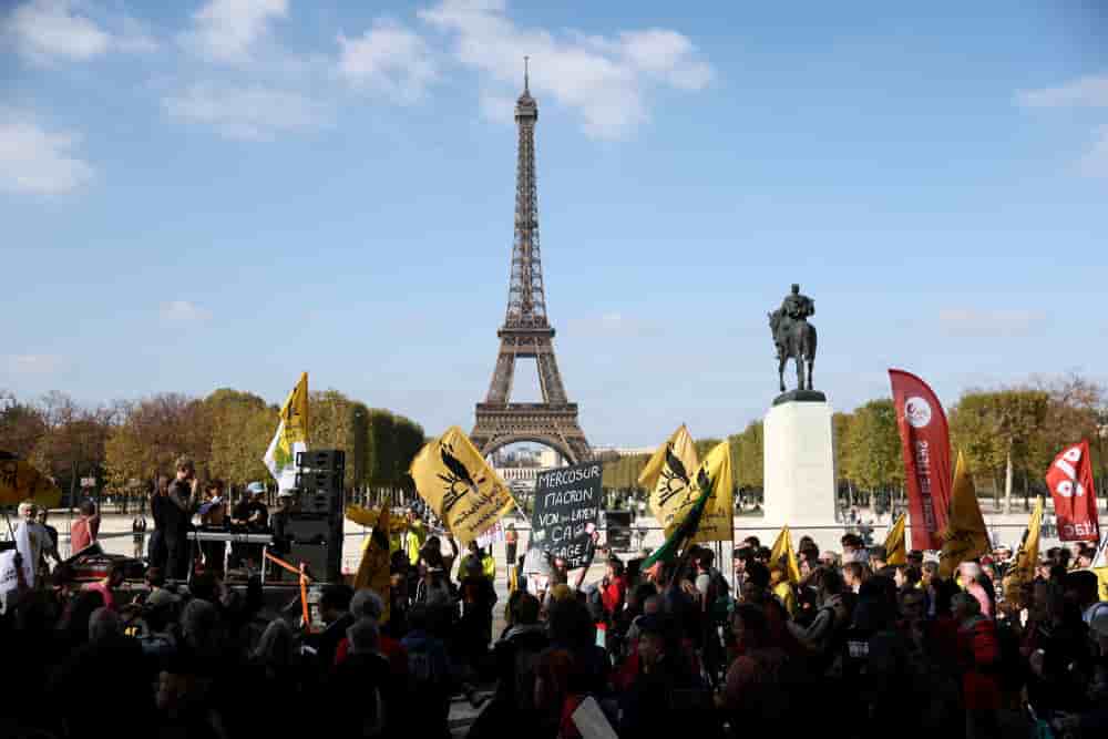 Des personnes se rassemblent le 14 octobre 2025 près de la Tour Eiffel lors d'une manifestation appelée par les agriculteurs français et la Confédération paysanne pour protester contre l'accord de libre-échange UE-Mercosur.