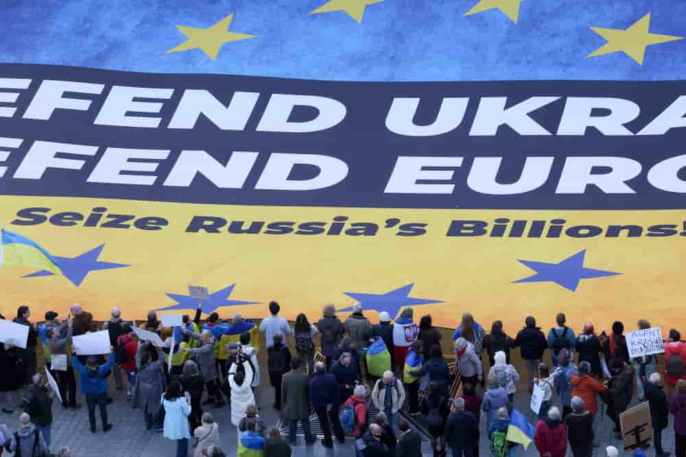 Des militants ukrainiens déploient une immense banderole à Bruxelles, exhortant les dirigeants européens à saisir les avoirs russes gelés afin de financer l’Ukraine dans son conflit contre la Russie, en mars 2025.