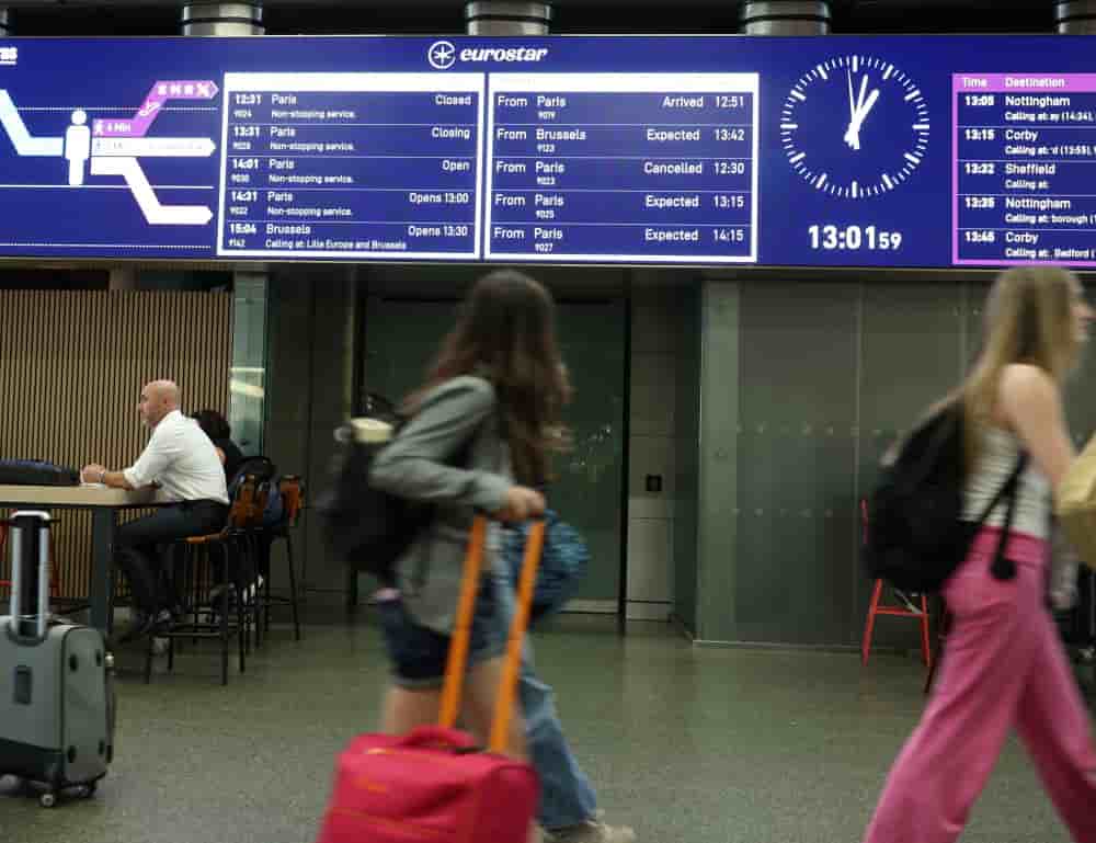 Des voyageurs passent devant un panneau indiquant l'annulation d'un train reliant Paris à Londres, à la gare internationale St. Pancras (photo d'archive ; juin 2025).