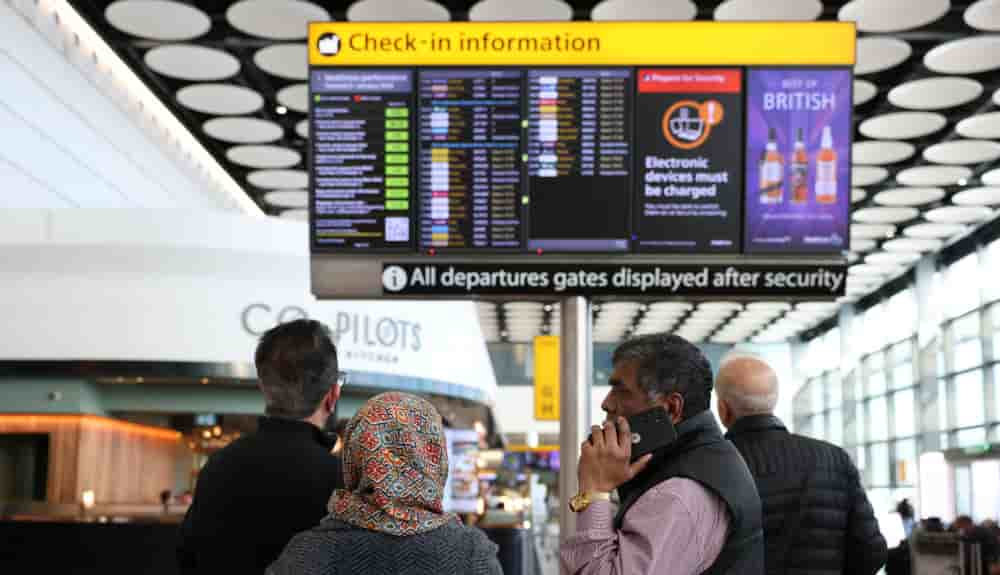 Des voyageurs consultent un tableau d’affichage indiquant les vols annulés vers les pays du Moyen-Orient en raison du conflit entre les États-Unis, Israël et l’Iran, au terminal 4 de l’aéroport d’Heathrow, le 2 mars 2026.