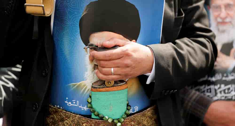 Au Yémen, le 6 mars 2026, un homme portant une affiche à l'effigie d.u défunt guide suprême iranien, l'ayatollah Ali Khamenei