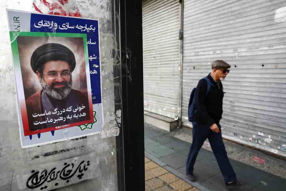 Un homme marche à côté d'une affiche à l'effigie du nouveau guide suprême iranien, Mojtaba Khamenei, dans le contexte du conflit israélo-américain avec l'Iran, à Téhéran, en Iran, le 22 mars 2026.