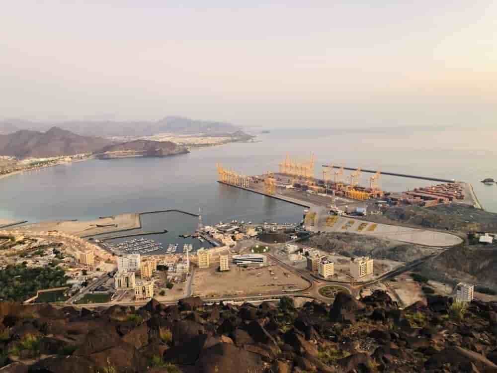 Port de Khor Fakkan (Émirats arabes unis). La saturation de ce hub stratégique du Golfe, ici vu depuis les monts Al Rabi, illustre la paralysie du fret maritime. Depuis le blocage du détroit d'Ormuz, les retards y dépassent 13 jours en moyenne.