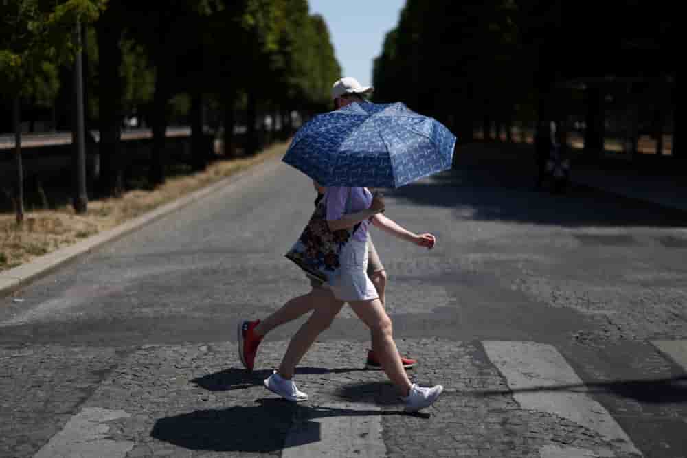 Des personnes, traversent un passage piéton à Paris, le 1er juillet 2025, alors qu'une vague de chaleur précoce frappe la France.
