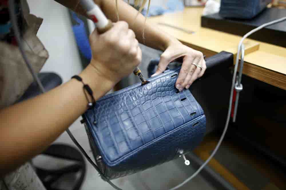 Une artisane travaille sur un sac Kelly à l'usine d'articles de luxe Hermès à Seloncourt (Doubs), le 4 octobre 2013. (Image d'illustration