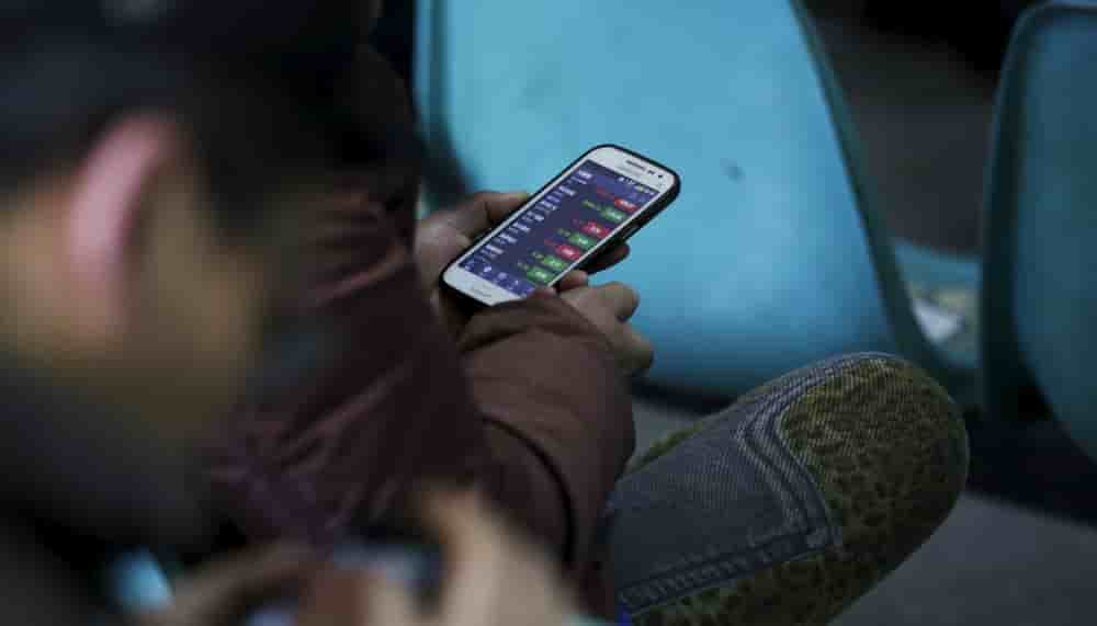 Image d'illustration d'investisseurs qui consultent le cours des actions sur leur téléphone portable.