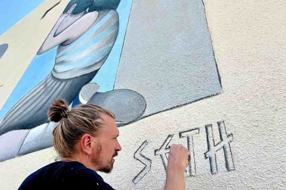 Seth signe une fresque murale de 12 mètres qu'il a peinte à Nicosie (Chypre) en juin 2024.