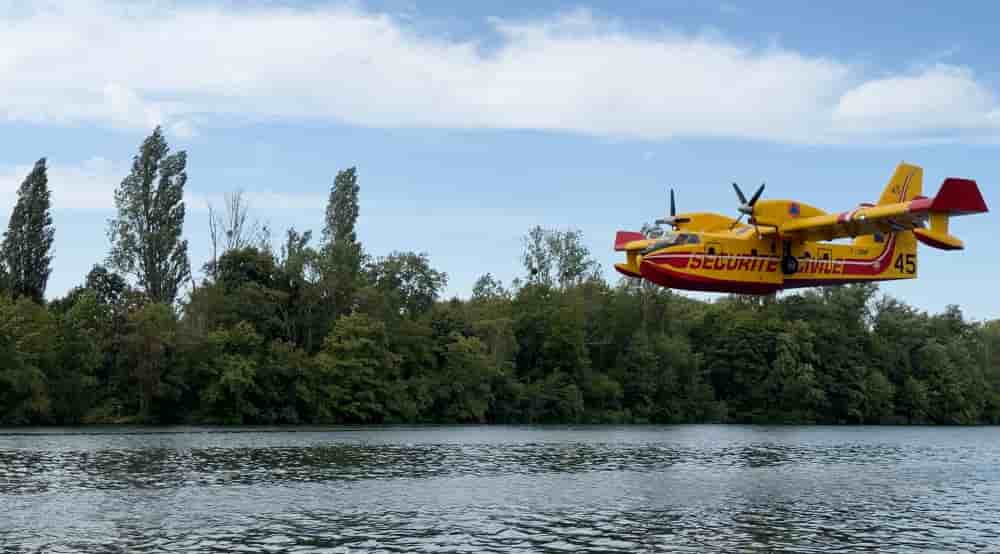 Un Canadair engagé sur le feu de la forêt de Fontainebleau survole la Seine, à Chartrettes, pour écoper de l'eau.