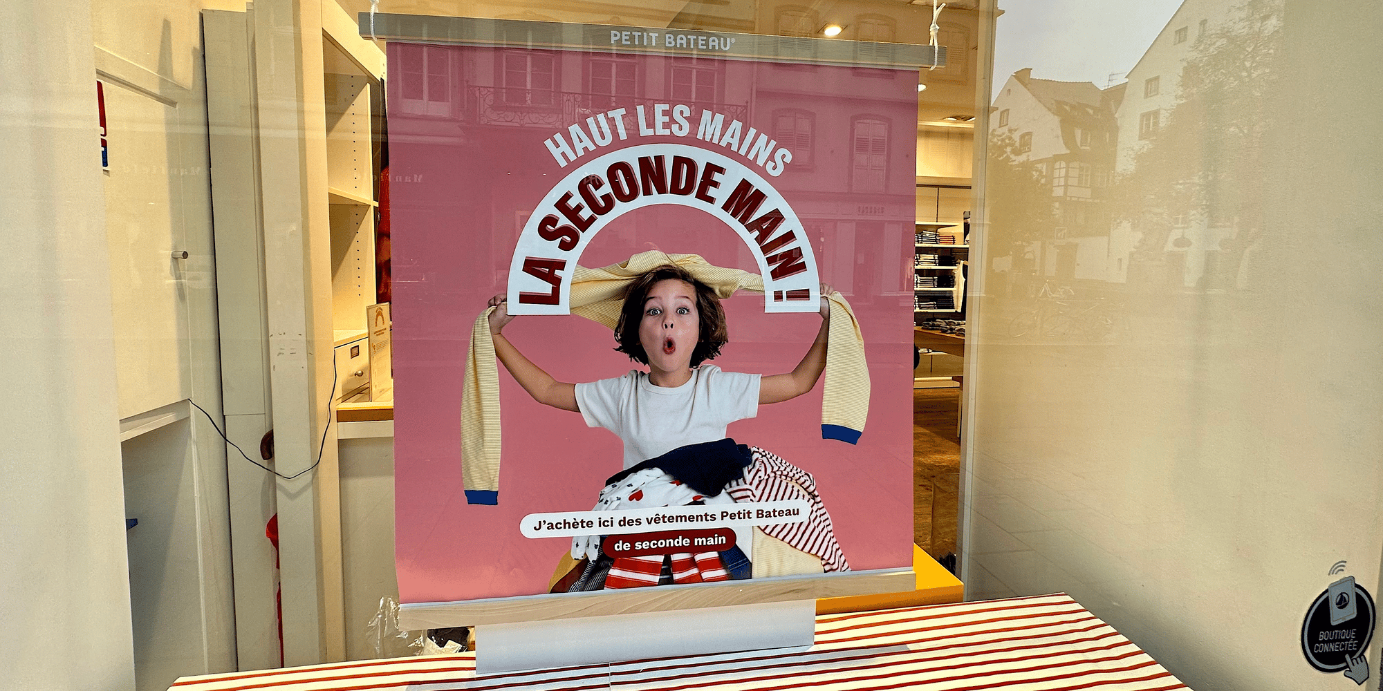 Une affiche apposée en vitrine informe les clients sur l'offre de seconde main, dans un magasin Petit Bateau à Strasbourg.