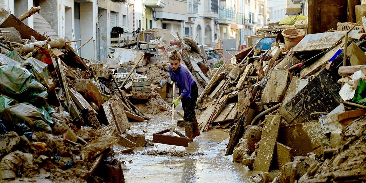 Une femme nettoie la boue parmi les débris dans une rue de Paiporta, au sud de Valence, dans l'est de l'Espagne, le 6 novembre 2024, à la suite d'inondations meurtrières.