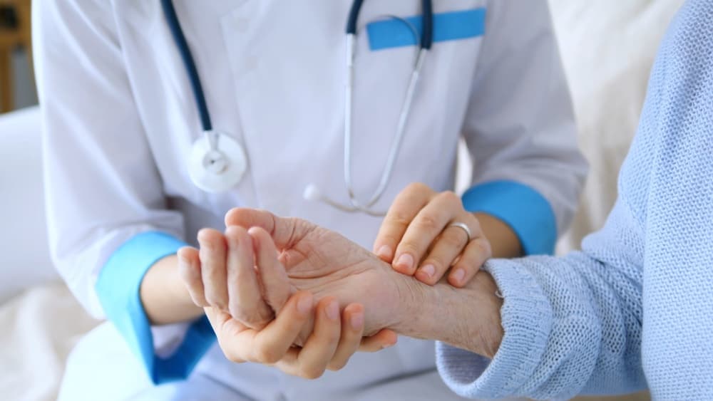 Female doctor measuring the pulse of a senior woman during a home visit, delivering compassionate healthcare and medical assistance tailored for elderly patients