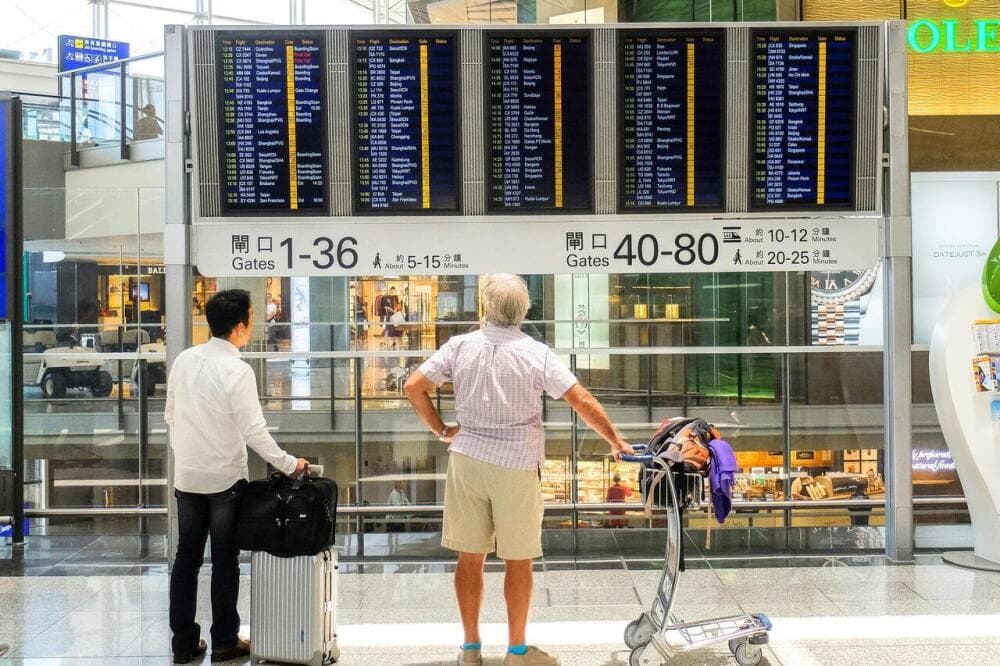 Des personnes devant un tableau d'embarquement à l'aeroport