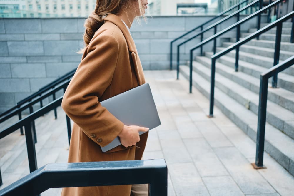 Close up young businesswoman in coat with laptop on city street - Close up young businesswoman in coat with laptop on street
