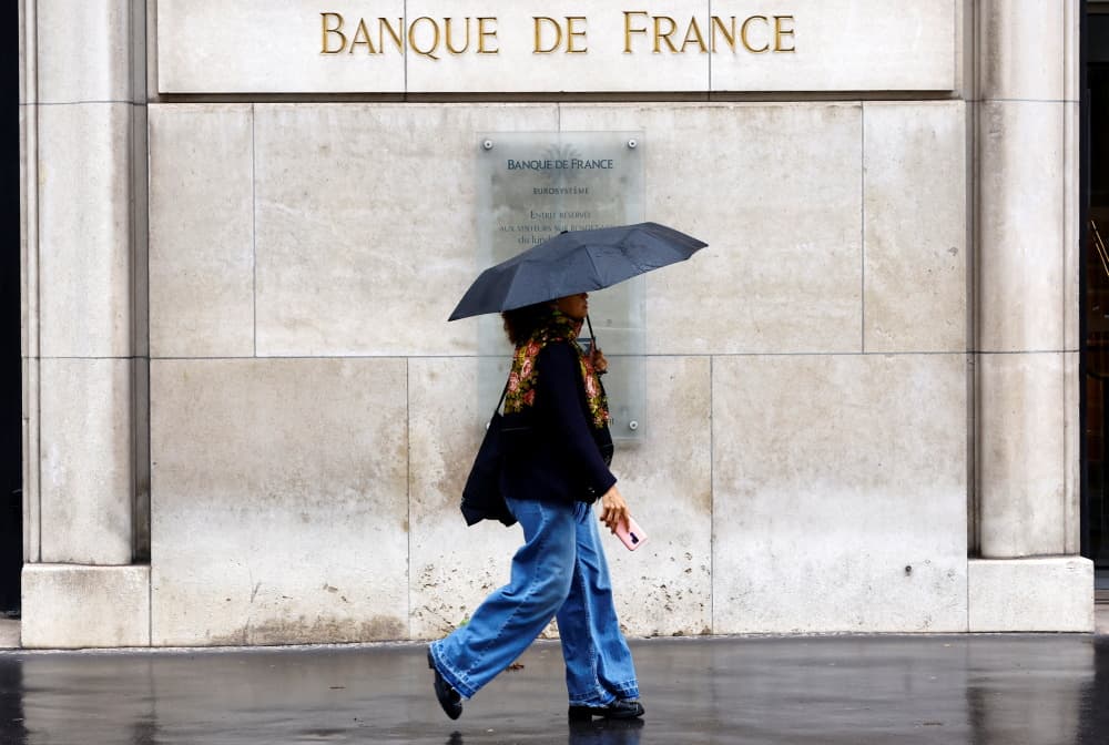 Une femme, parapluie à la main, passe devant le bâtiment de la Banque de France à Paris, le 25 septembre 2024.