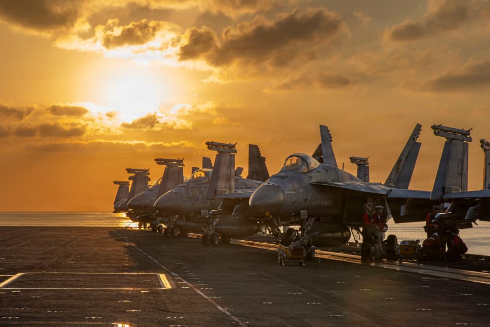Des chasseurs de l’US Navy stationnés sur le pont d’envol de l’USS Abraham Lincoln, le 3 mars 2026, avant une sortie nocturne dans le cadre de l’opération Epic Fury. Cette esthétique du « soleil couchant », récurrente dans les images fournies par le...