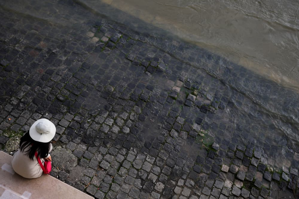 Une femme est assise sur un banc sur les berges inondées de la Seine, à Paris, le 23 février 2026.