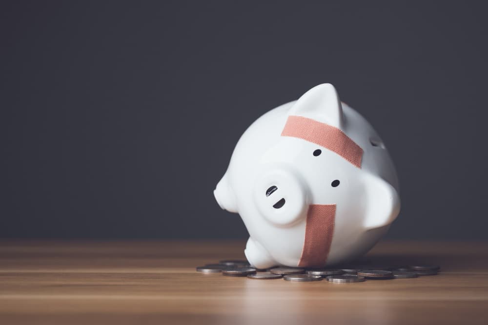 Financial problem, Bankrupt or fail in business concept. White piggy bank with plastic adhesive bandages on wooden desk with dark copy space wall background. Fail, Bankrupt or unsuccessful idea. - Financial problem, Bankrupt or fail in business...