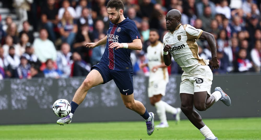 L'attaquant du Paris Saint-Germain Khvicha Kvaratskhelia devance le Lensois Malang Sarr lors du match de Ligue 1 opposant le PSG au RC Lens, au Parc des Princes, à Paris, le 14 septembre 2025.