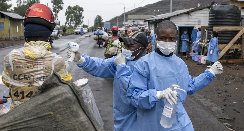 Des agents de santé déployés en réponse à l'épidémie d'Ebola vérifient la température et fournissent du désinfectant pour les mains aux motocyclistes qui passent par le point de contrôle de Kanyaruchinya, au nord de Goma.