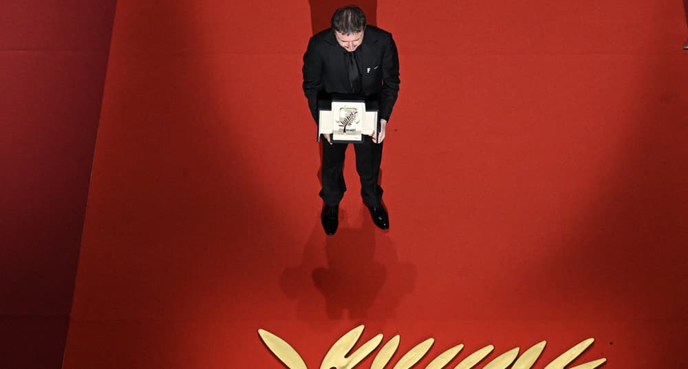 Le réalisateur Cristian Mungiu célèbre sa palme d'or sur scène.