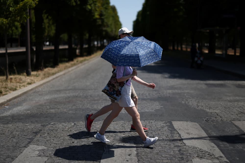 Des personnes, traversent un passage piéton à Paris, le 1er juillet 2025, alors qu'une vague de chaleur précoce frappe la France.
