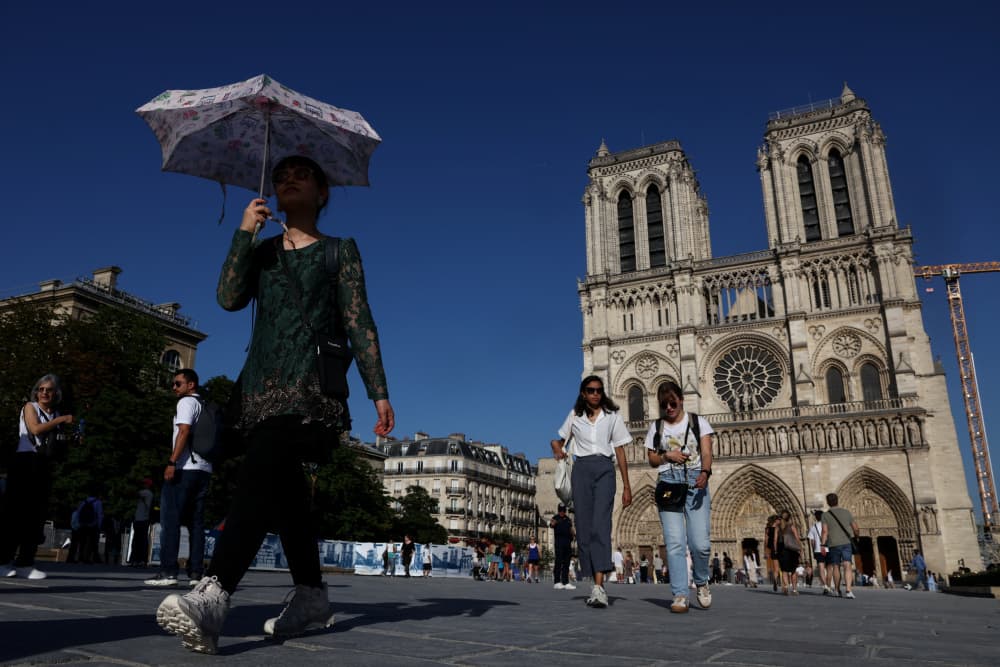 Une personne s'abrite sous un parapluie devant la cathédrale Notre-Dame de Paris, en pleine vague de chaleur, le 26 mai 2026.