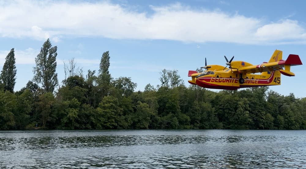 Un Canadair engagé sur le feu de la forêt de Fontainebleau survole la Seine, à Chartrettes, pour écoper de l'eau.